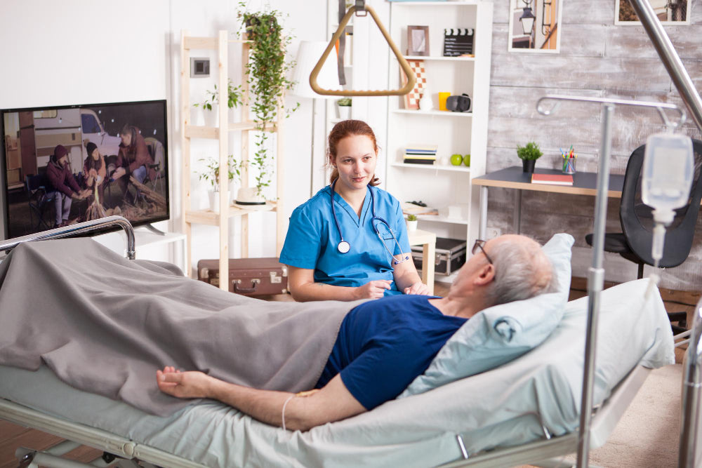 Infirmière à domicile discutant avec un patient âgé allongé dans un lit médicalisé. 